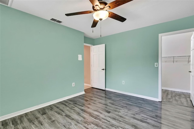 unfurnished bedroom with baseboards, visible vents, wood finished floors, and a closet