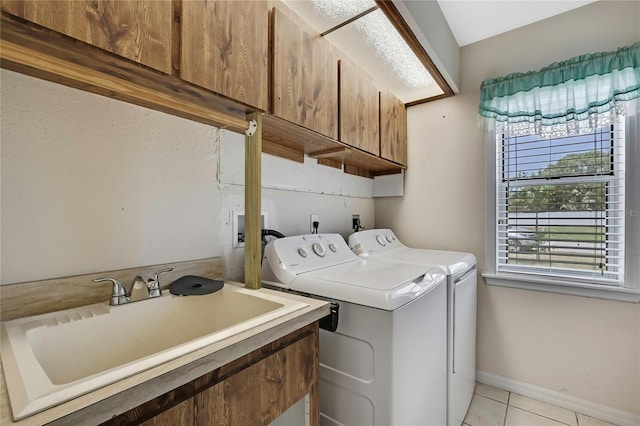 washroom featuring a sink, cabinet space, light tile patterned floors, baseboards, and washer and dryer