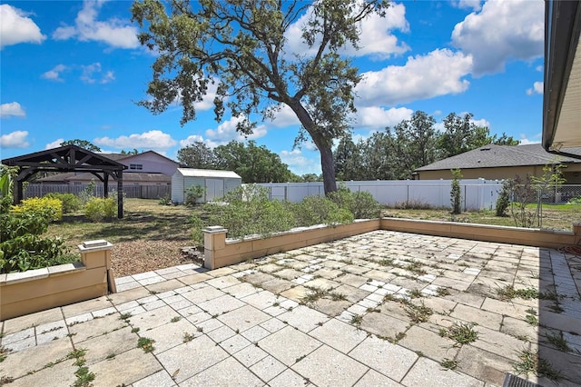 view of patio / terrace with an outdoor structure, a storage shed, a gazebo, and a fenced backyard