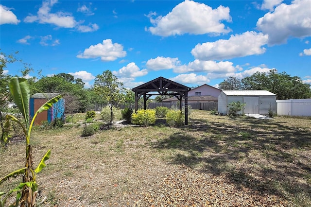 view of yard featuring a gazebo, a fenced backyard, an outbuilding, and a storage shed