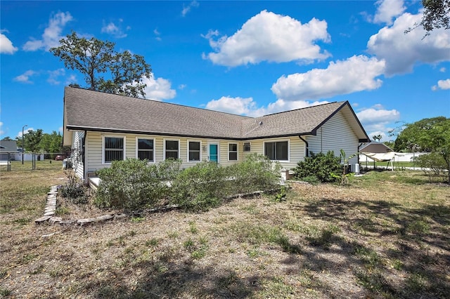 rear view of house with central AC and roof with shingles