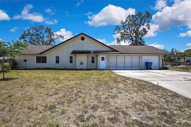 ranch-style house with driveway, roof with shingles, a front yard, and an attached garage