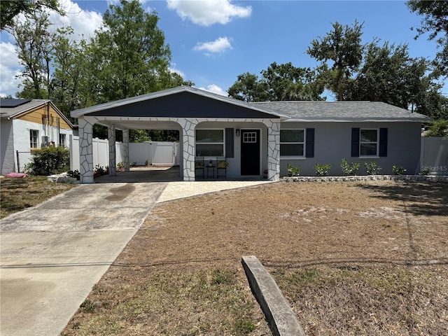 single story home with concrete driveway, fence, a porch, and a carport
