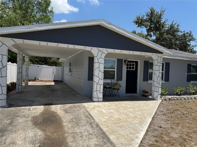 view of front facade with fence, concrete block siding, a gate, a carport, and driveway