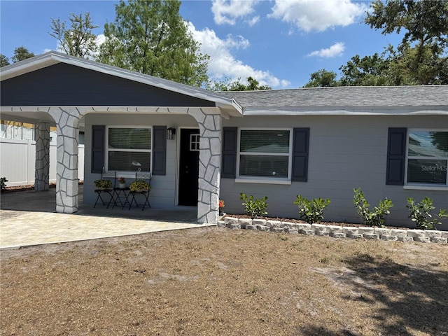 ranch-style home with a porch and a shingled roof