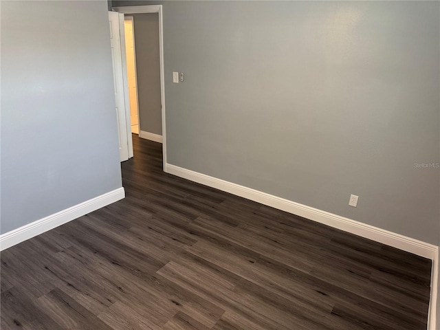 unfurnished room with baseboards and dark wood-style flooring