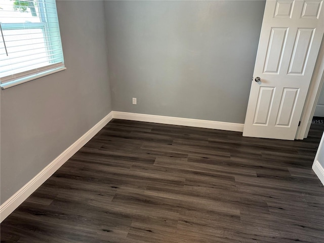 spare room with baseboards and dark wood finished floors