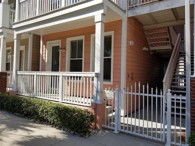 view of side of property featuring fence, stairs, a porch, and a gate