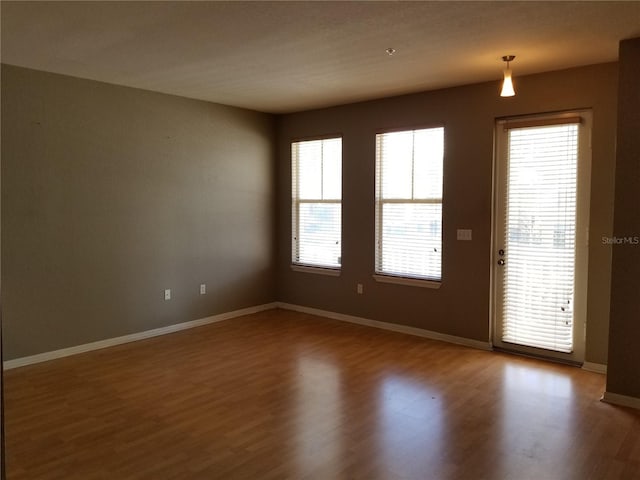 spare room with baseboards and wood finished floors