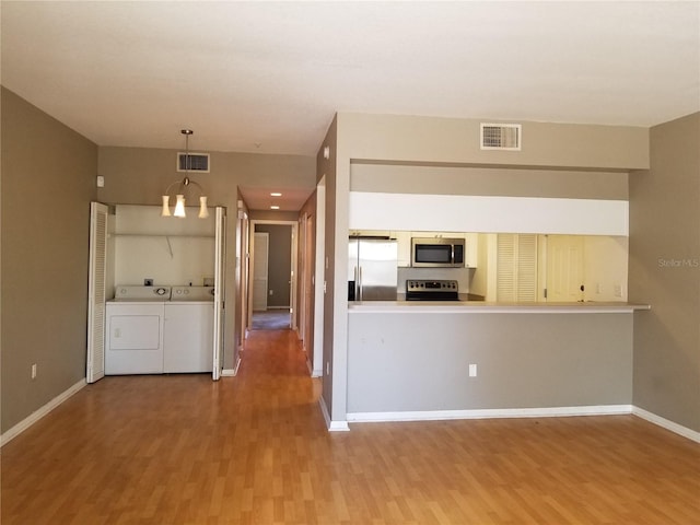kitchen with appliances with stainless steel finishes, wood finished floors, and visible vents