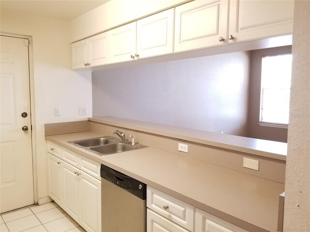 kitchen with stainless steel dishwasher, light countertops, a sink, white cabinetry, and light tile patterned flooring