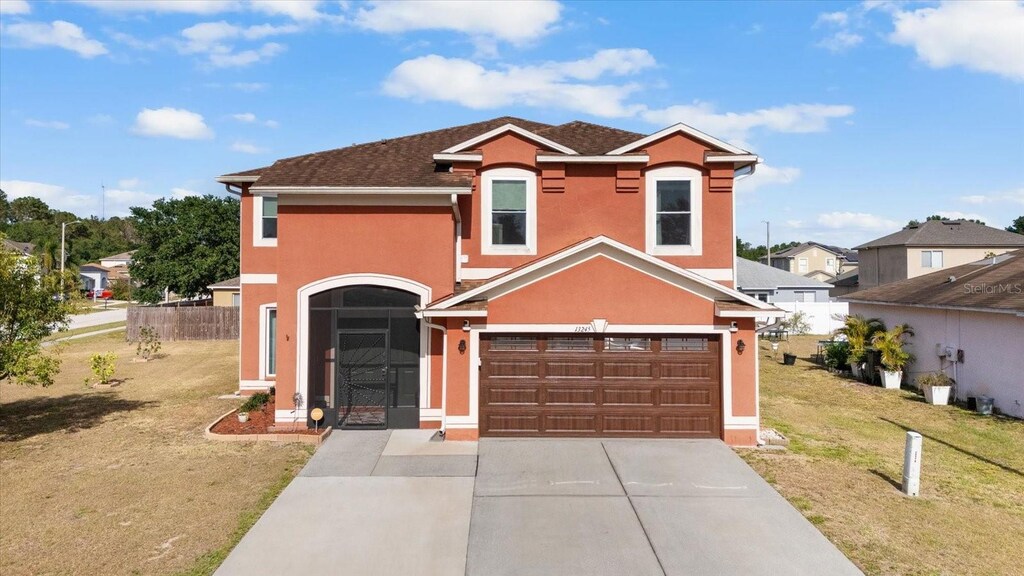 13245 Prestwick Creek Dr, Riverview, FL 33579 - traditional home featuring a front lawn, stucco siding, driveway, an attached garage, and fence