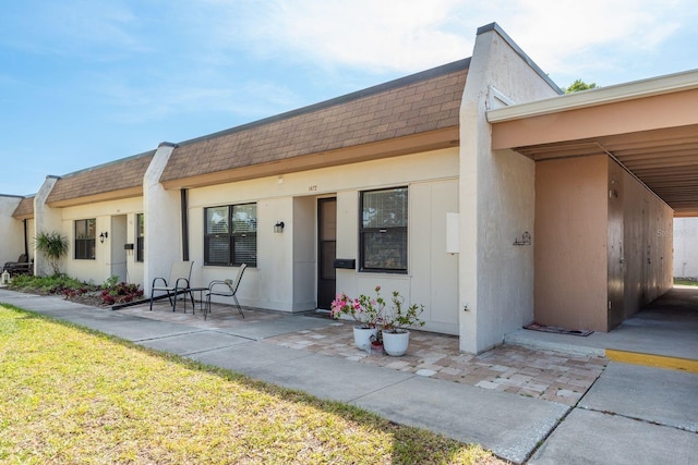 townhome / multi-family property with mansard roof, a shingled roof, and stucco siding