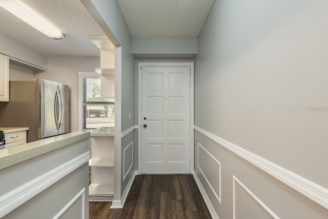 doorway featuring dark wood-style flooring and a textured ceiling