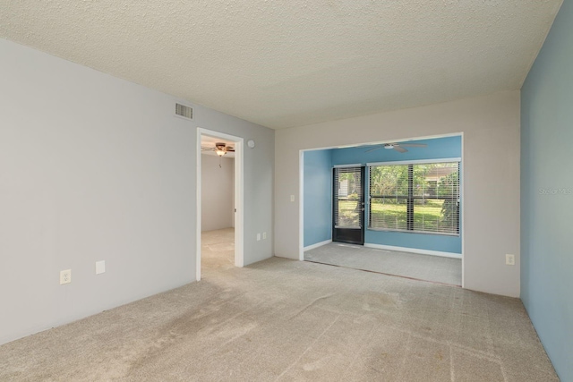 empty room featuring a textured ceiling, visible vents, ceiling fan, and carpet