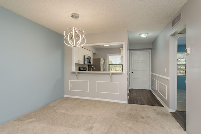 interior space featuring dark colored carpet, visible vents, plenty of natural light, and a notable chandelier