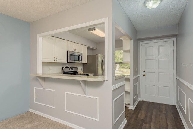 kitchen featuring white cabinets, a textured ceiling, appliances with stainless steel finishes, and light countertops