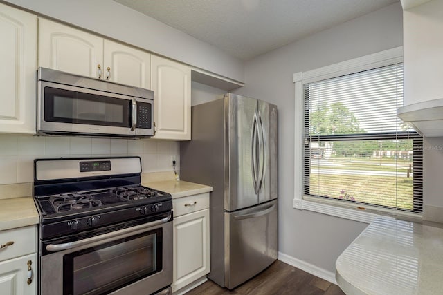 kitchen with dark wood finished floors, backsplash, stainless steel appliances, and light countertops