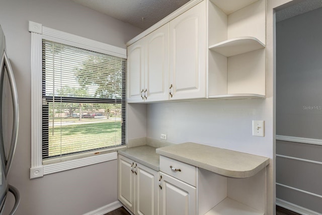 kitchen featuring open shelves, light countertops, a textured ceiling, white cabinets, and freestanding refrigerator