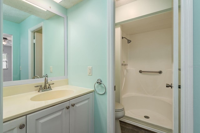 bathroom with toilet, vanity, a shower stall, and a textured ceiling