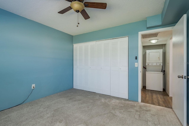 unfurnished bedroom featuring stacked washer / dryer, visible vents, ceiling fan, a closet, and carpet