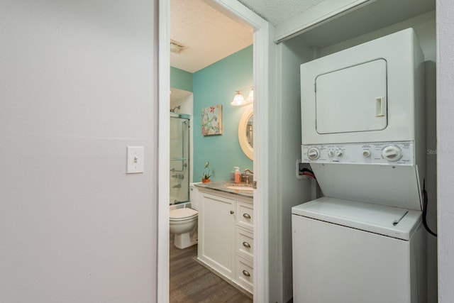 washroom with stacked washer and dryer, a textured ceiling, a sink, dark wood-style flooring, and laundry area