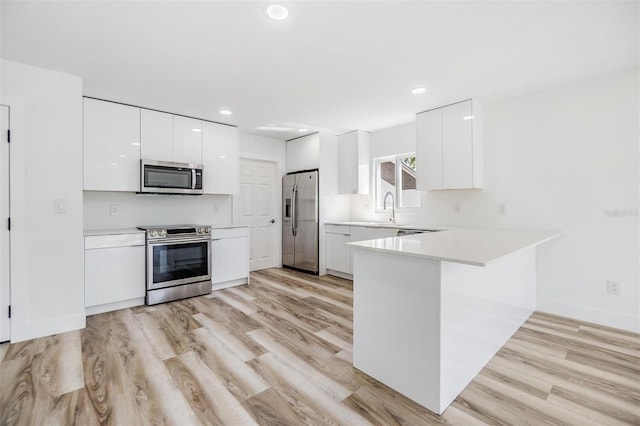 kitchen featuring modern cabinets, stainless steel appliances, a peninsula, light countertops, and white cabinets
