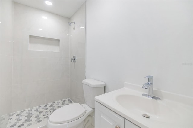 full bath featuring tiled shower, toilet, and vanity
