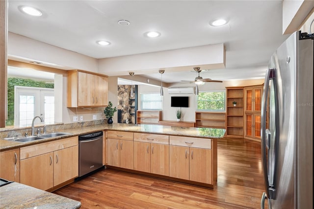 kitchen with a sink, appliances with stainless steel finishes, light brown cabinetry, and a peninsula