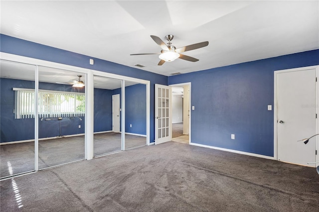 unfurnished bedroom featuring ceiling fan, visible vents, carpet floors, baseboards, and two closets