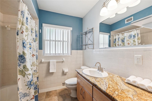 bathroom with vanity, toilet, a shower with shower curtain, tile walls, and visible vents