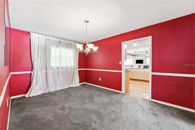 carpeted spare room featuring baseboards and an inviting chandelier