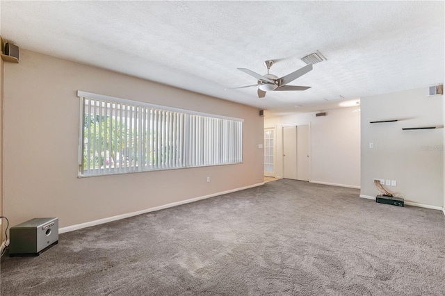 carpeted spare room with baseboards, a ceiling fan, a textured ceiling, and visible vents