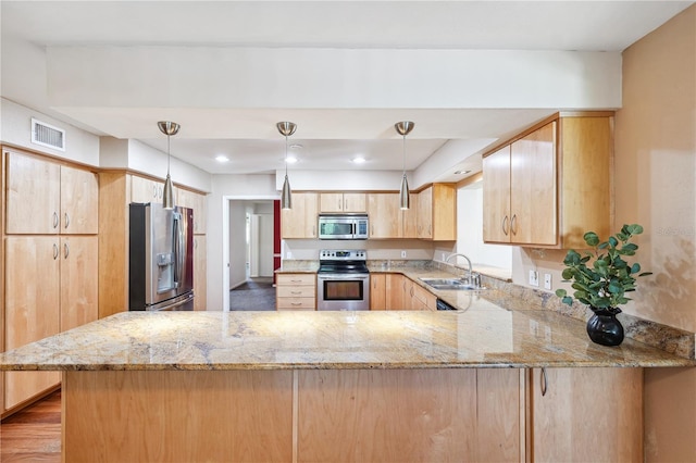 kitchen with a sink, appliances with stainless steel finishes, light brown cabinetry, and light stone counters