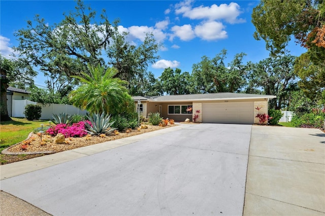 ranch-style house with fence, an attached garage, and driveway