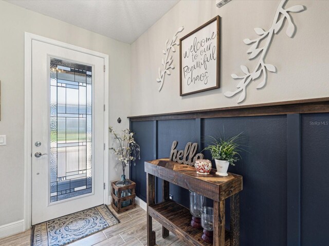 doorway featuring baseboards and light wood finished floors