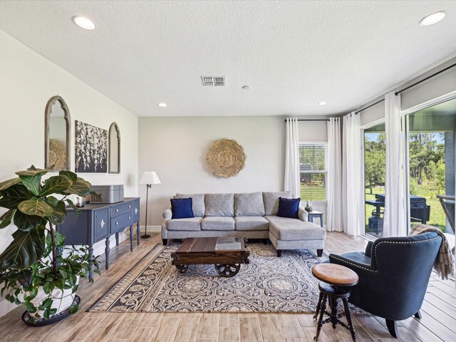 living area featuring recessed lighting, a textured ceiling, and wood finished floors