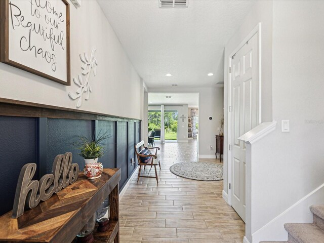 hall with visible vents, baseboards, wood tiled floor, stairway, and recessed lighting