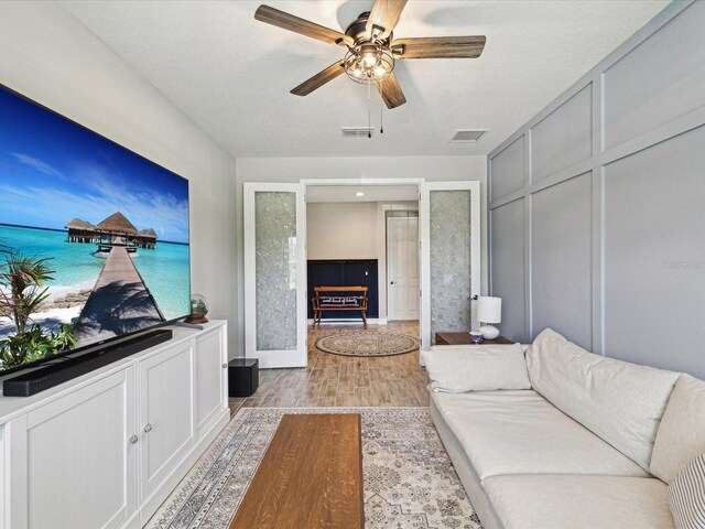 living area featuring baseboards, ceiling fan, light wood-type flooring, and visible vents