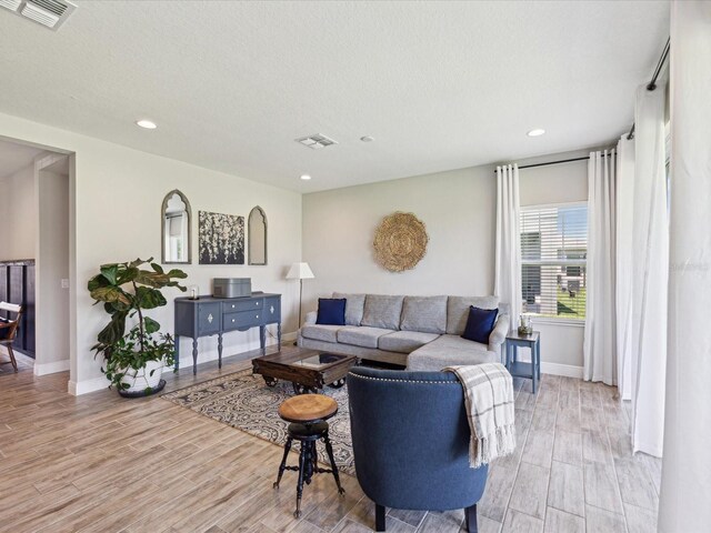 living room featuring recessed lighting, baseboards, visible vents, and light wood-style floors
