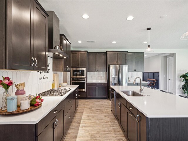 kitchen featuring light countertops, a sink, dark brown cabinetry, and stainless steel appliances