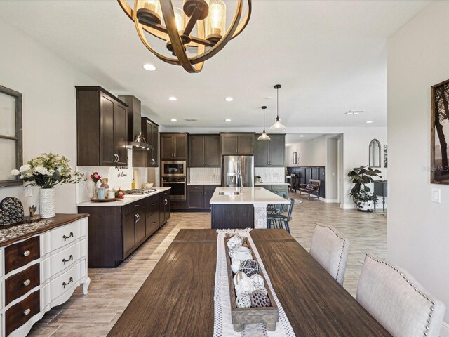 dining area with recessed lighting, light wood-type flooring, baseboards, and an inviting chandelier