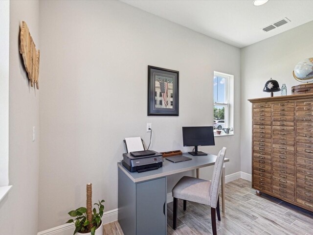 office area featuring visible vents, light wood-style floors, and baseboards