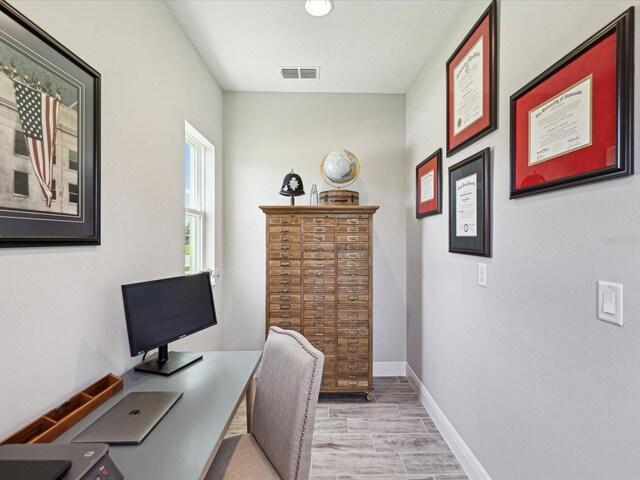 office space with light wood-style floors, baseboards, and visible vents