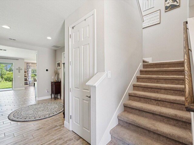 stairway with recessed lighting, baseboards, visible vents, and wood finished floors