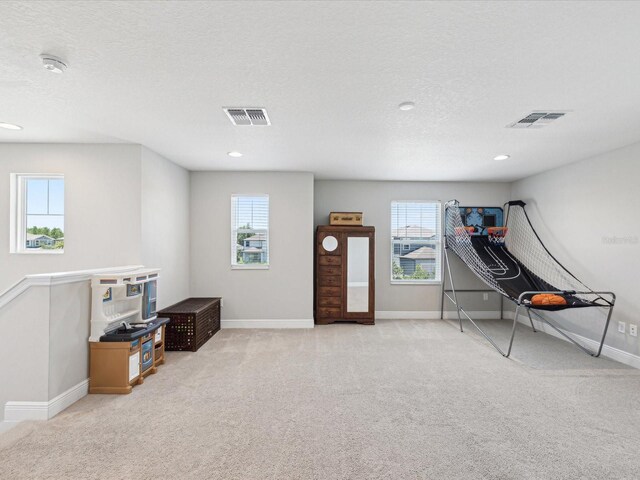 rec room with carpet floors, visible vents, and plenty of natural light