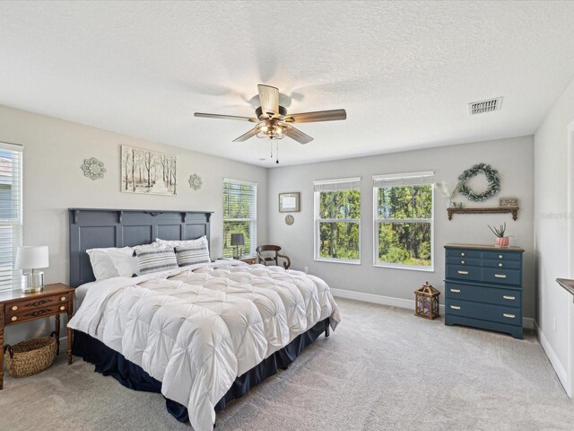 bedroom featuring ceiling fan, visible vents, light carpet, and baseboards