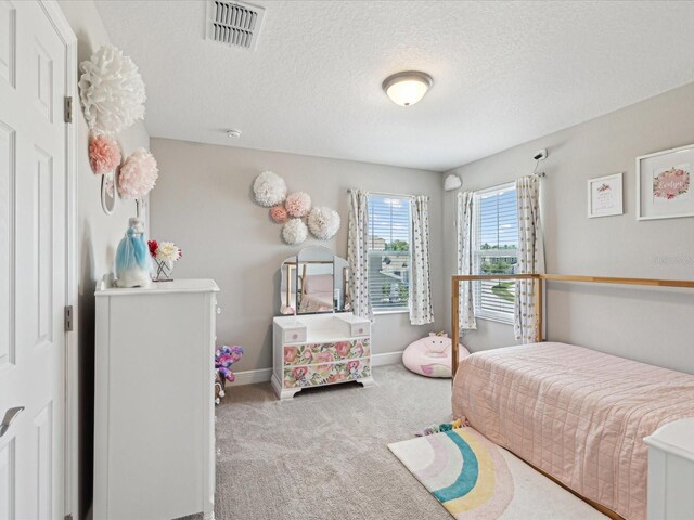carpeted bedroom with visible vents, a textured ceiling, and baseboards