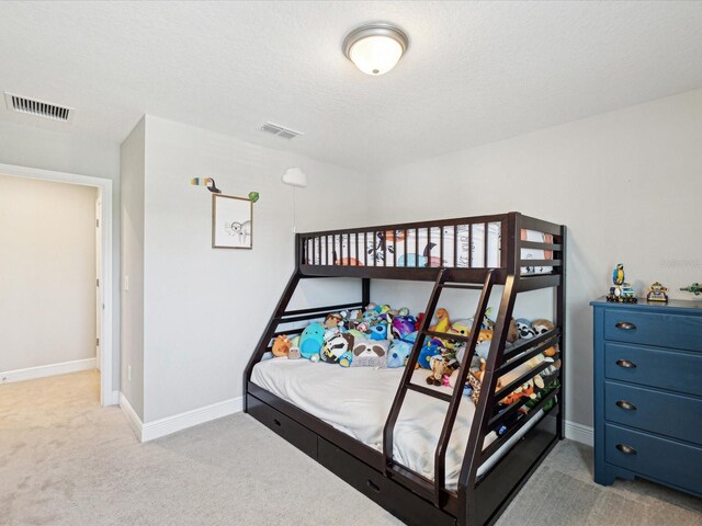 bedroom featuring a textured ceiling, baseboards, visible vents, and carpet