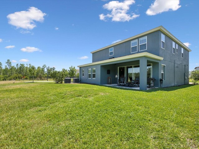 back of property with a lawn, a patio area, and stucco siding